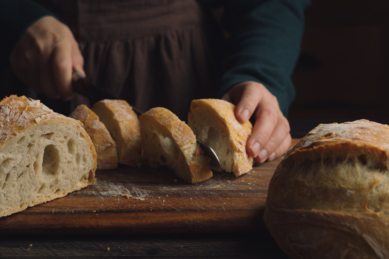 Mastering the First Impression: Your intriguing post title goes here Close-up of hands slicing fresh artisan bread loaf on a wooden board.